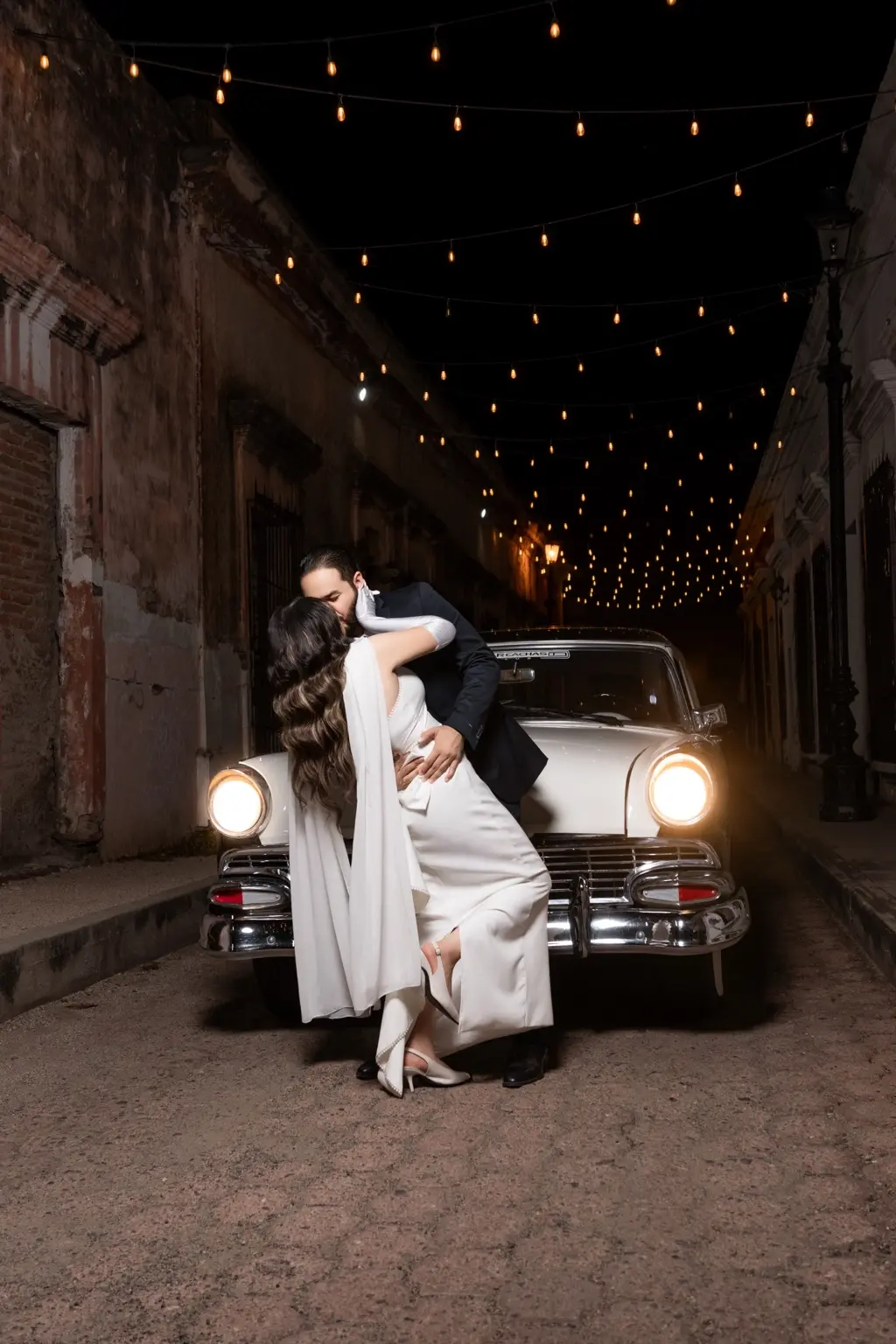 Martha Karina y Elve Jesús besándose frente a un auto clásico