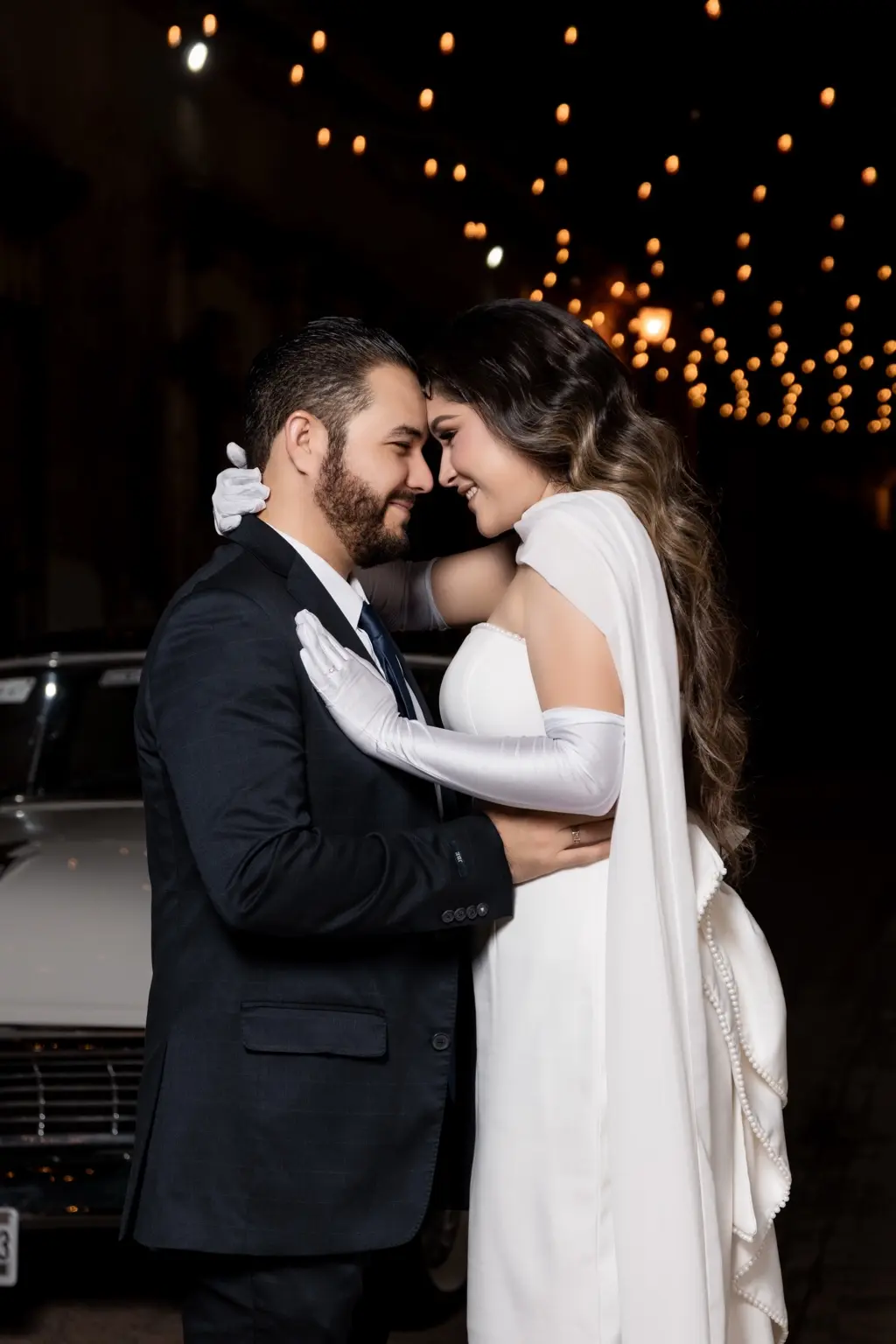 Martha Karina y Elve Jesús abrazados frente al auto clásico